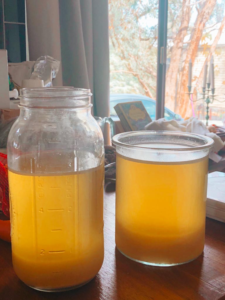 Two glass jars filled with golden chicken broth