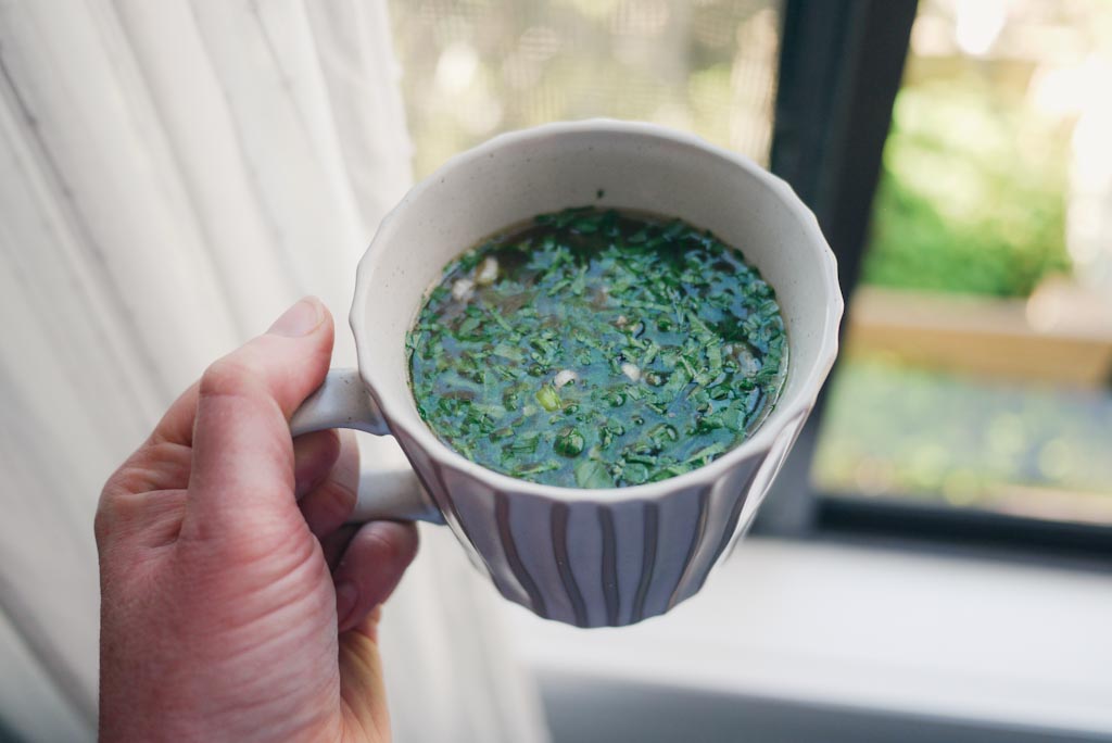 Cup of miso soup with greens in mug - a warming breastfeeding snacking option