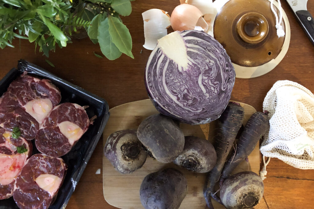 Ingredients for Ukrainian borscht: osso bucco, beetroot, purple carrots, purple cabbage, and assorted herbs.