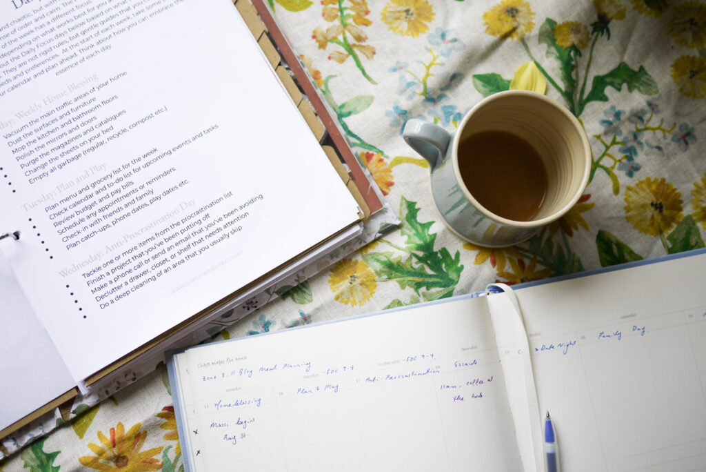 Home management system in action: planning the week with a cup of tea in paper diary and home management folder open. 