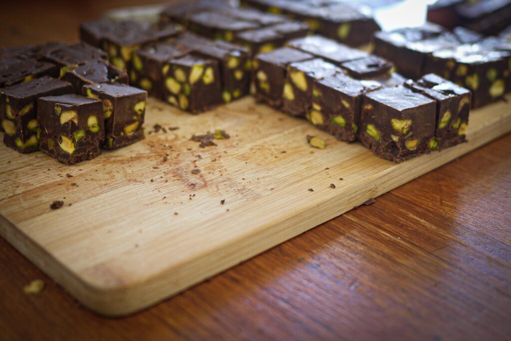 Squares of pistachio fudge on a chopping board.