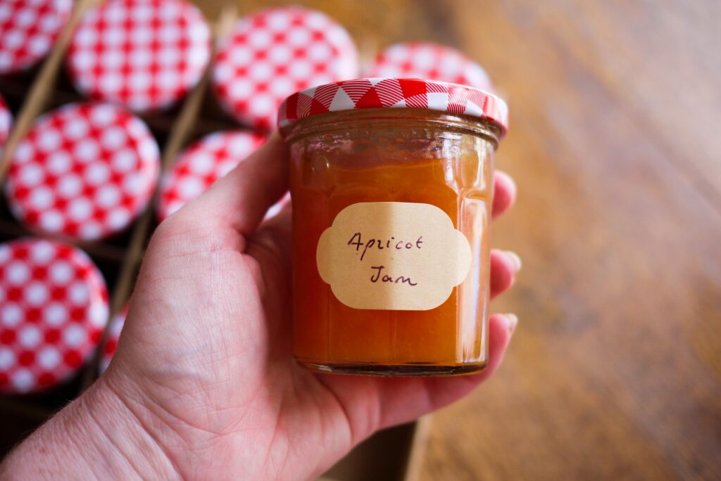 Hand holding a jar of apricot jam