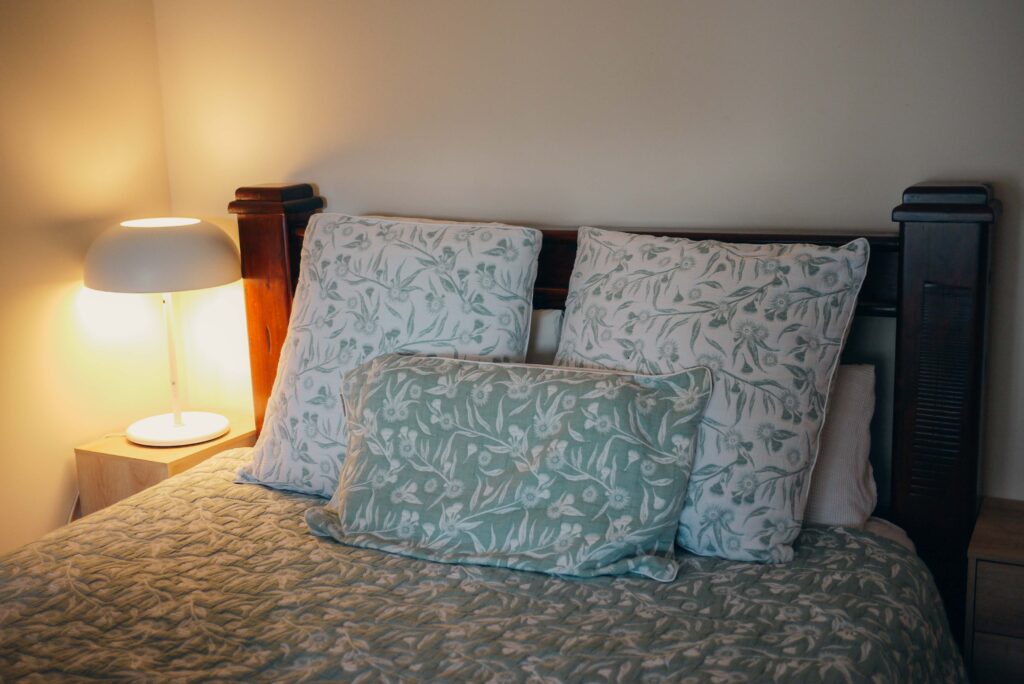 Close-up of a cozy bed with fresh crisp sheets and a soft lamp, inviting relaxation and self-care